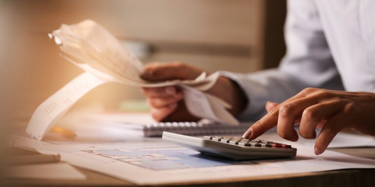 closeup economist using calculator while going through bills taxes office 2